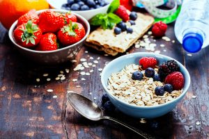 diet breakfast - bowls of oat flake, berries and fresh milk on wooden background - health and diet concept