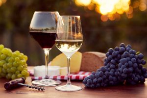 Two glasses of white and red wine with food at sunset, toned